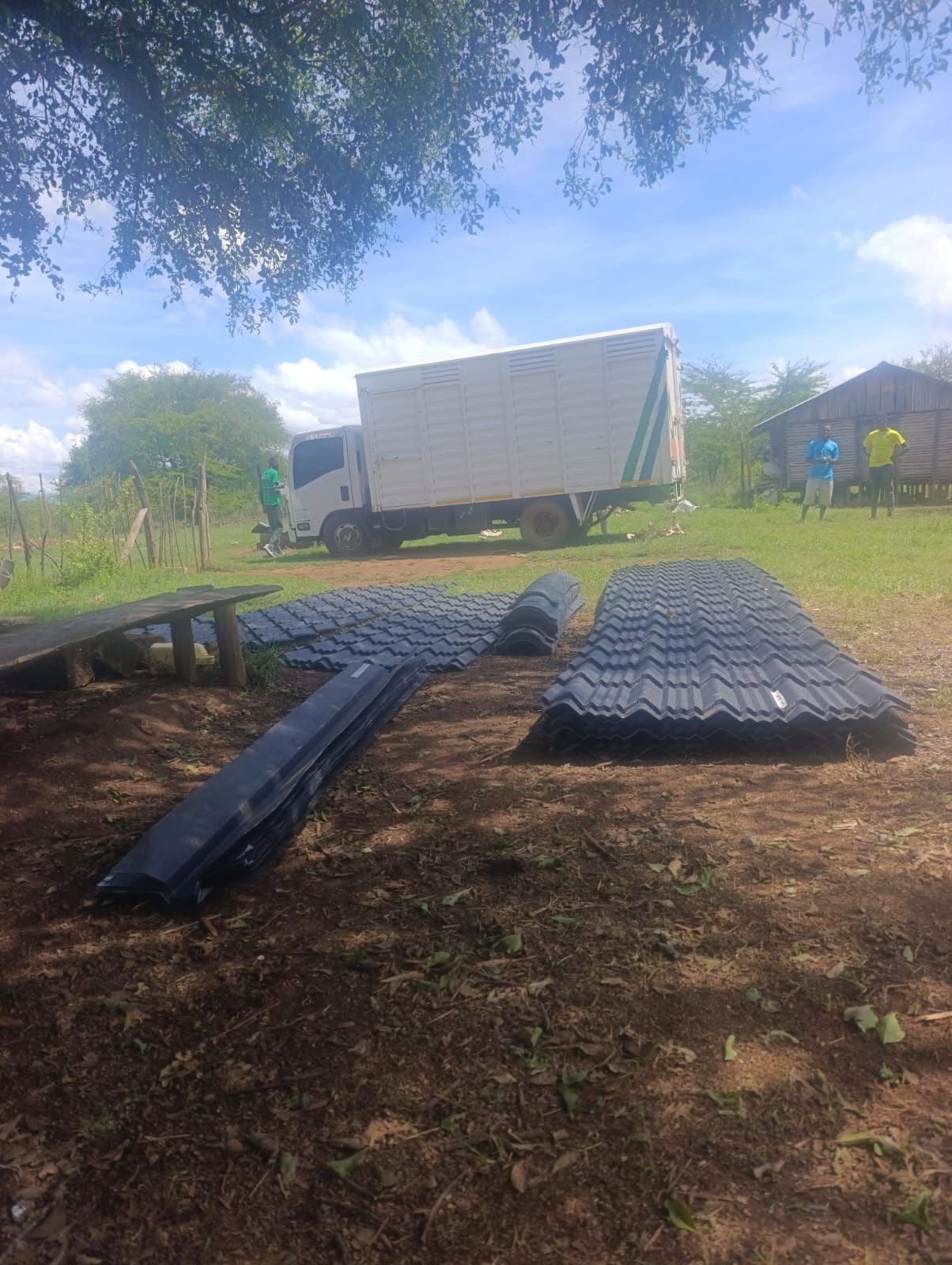 Charcoal stone-coated tiles and ridge flashings dropped off in a village compound by Tranquility Mabati truck