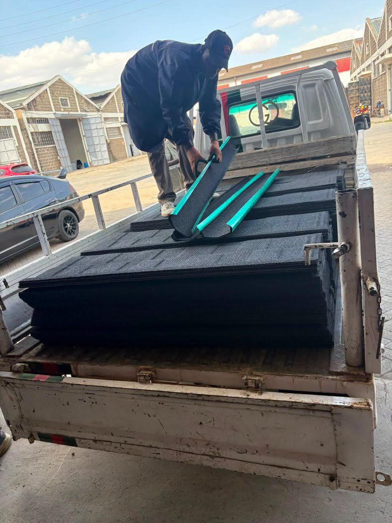 Crew loading black stone-coated roofing tiles and green ridge caps onto a pickup at the factory