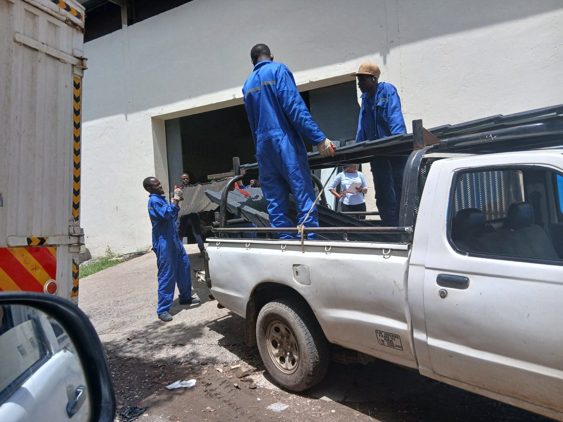 Crew loading stone-coated roofing tiles onto a customer pickup