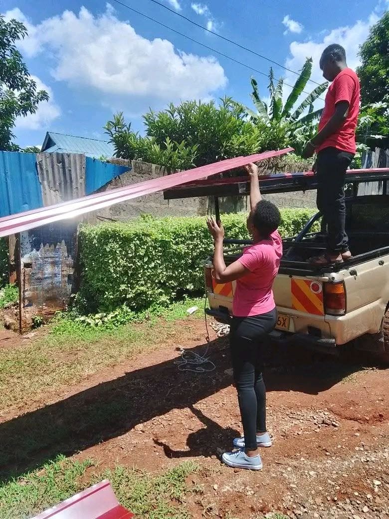 Workers loading red box-profile mabati onto a pickup